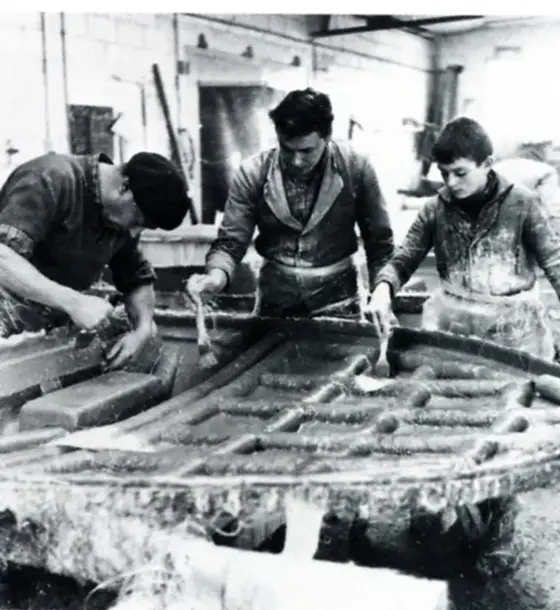 Three boatbuilders laying up a polyester hull by hand